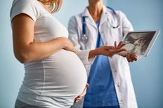 Doktor kadın hamile bir kadına bir ultrason resmi gösteriyor.