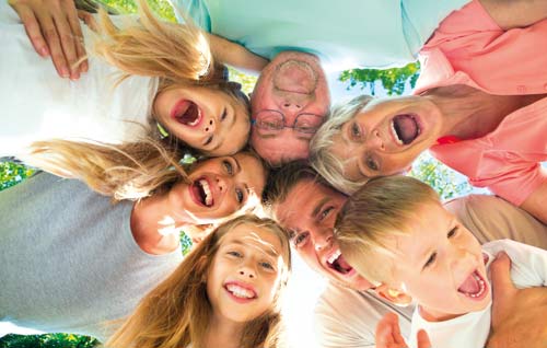 Eine Familie, bestehend aus drei Kindern, Eltern und Großeltern, schauen von oben lachend in die Kamera