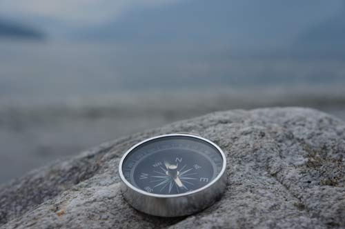Ein Kompass liegt auf einem Stein.
