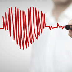 Ein Arzt malt mit einem roten Edding ein Herz.