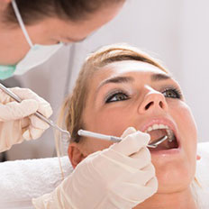 Eine Zahnärztin kontrolliert die Zähne einer Patientin.