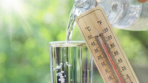 Water being poured into a glass and the thermometer shows 38 degrees.