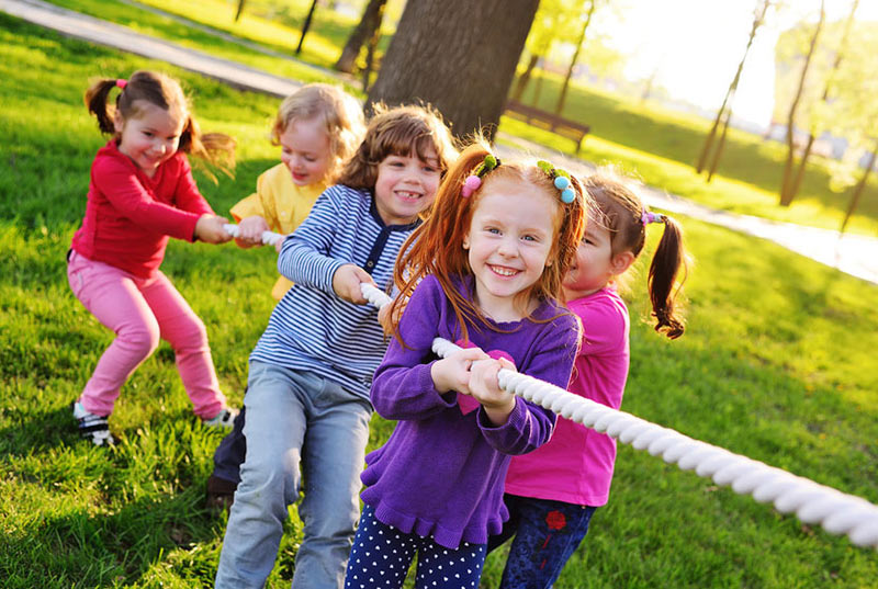 Kinder spielen draußen und ziehen an einem Seil