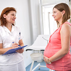 Гинеколог обсуждает результаты обследования с беременной женщиной.