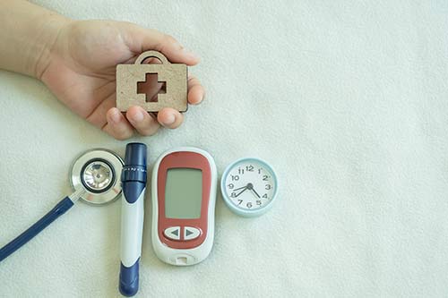 Устройство для измерения уровня глюкозы в крови и ланцет лежат рядом со стетоскопом.