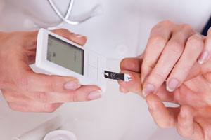 Врач измеряет уровень сахара в крови пациента.