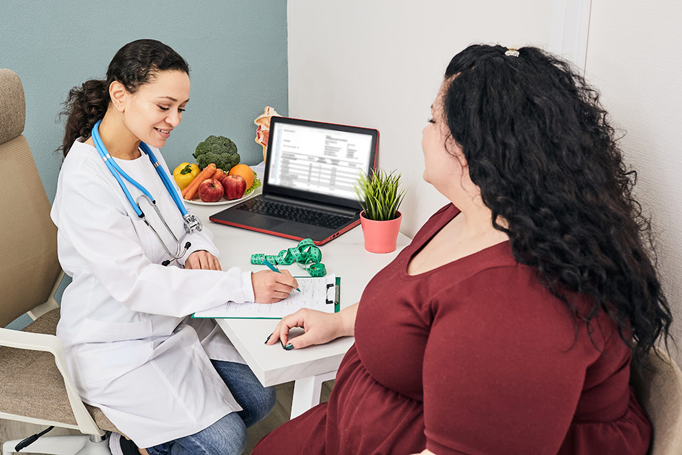 An overweight woman talking to a doctor.
