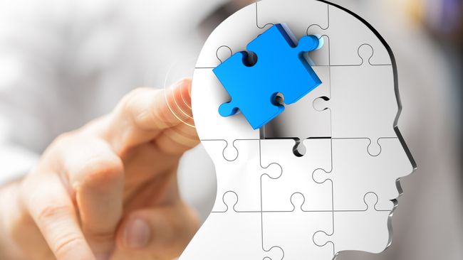 Kopf setzt sich aus verschiedenen Puzzleteilen zusammen. Ein Puzzleteil ist hervorgehoben in blauer Farbe. Eine Hand zeigt auf das Puzzleteil.