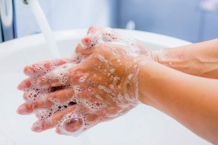 Hände, die mit Wasser und Seife an einem Waschbecken gewaschen werden.