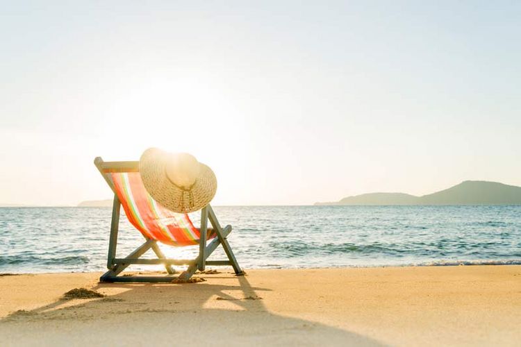 Ein Liegestuhl steht an einem sonnigen Strand.